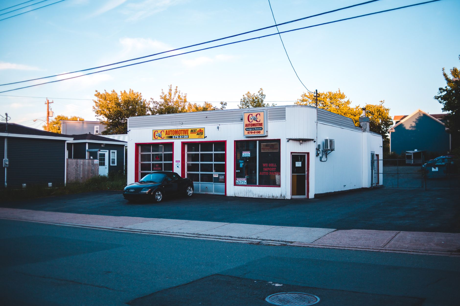 Automotive repair shop with parked sportscar at sunset in residential area